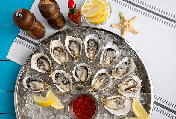 Fresh oysters on ice with lemon wedges and sauce ready to eat
